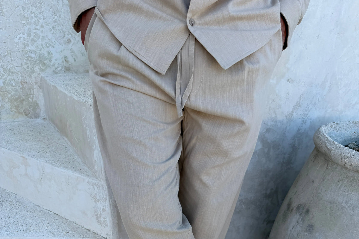 Pantalon en lin sable porté avec une chemise assortie, en lumière rasante