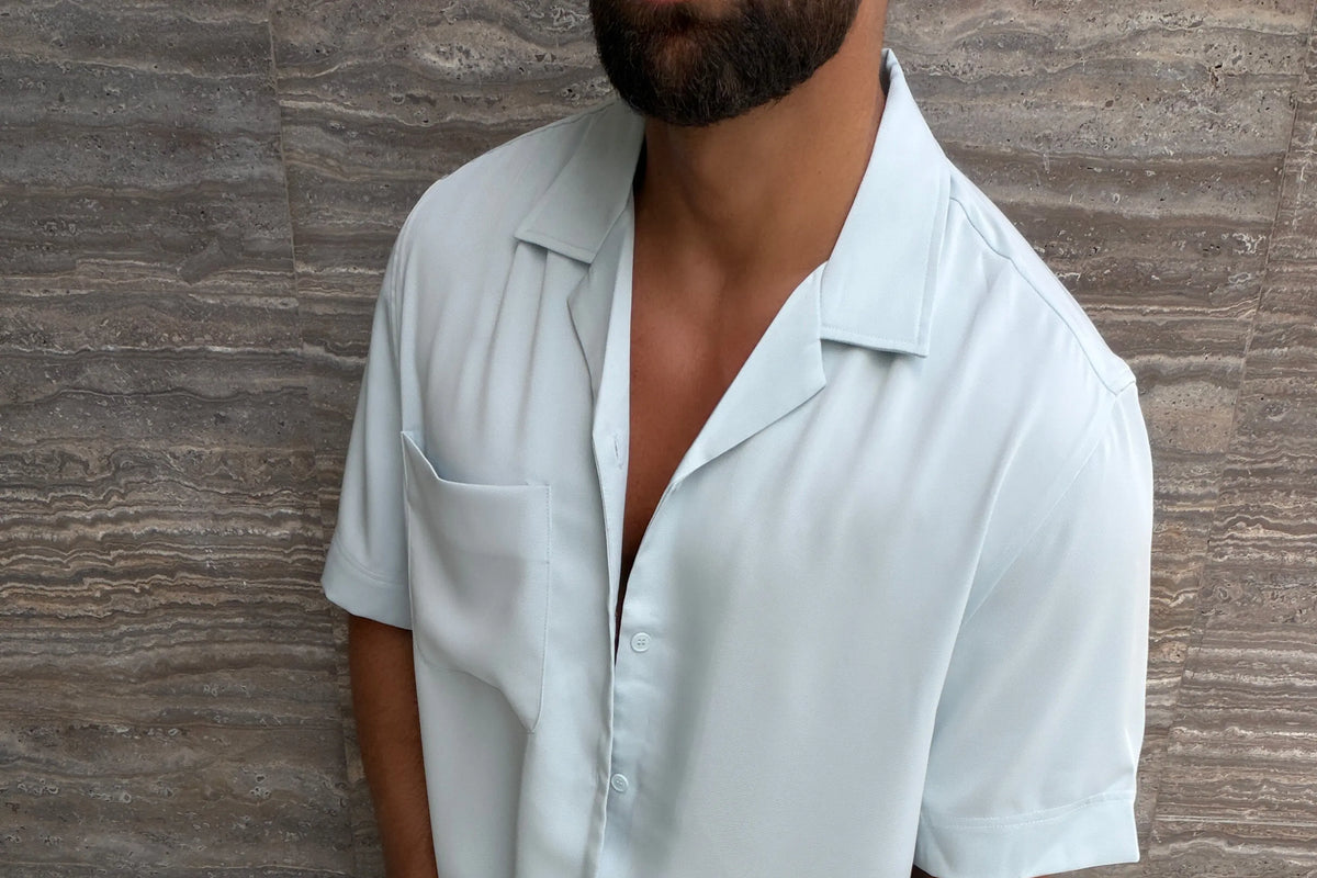 Homme en chemise bleu clair à col cubain, col ouvert et posé à plat sur les épaules